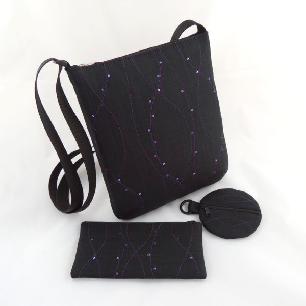 černá textilní kabelka crossbody, pouzdro na mobilní telefon a kulatá peněženka, zdobeno fialovým prošíváním a drobnými fialovými flitry