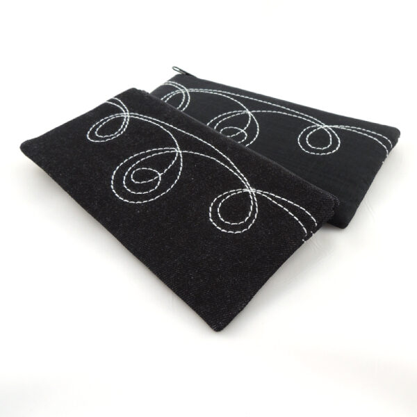 Černé textilní pouzdro na mobilní telefon, ušitéz rifloviny nebo ze softshellu, bílé proštepované ornamenty.